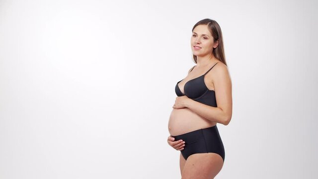 Young, happy and healthy pregnant woman on white background. Studio video. Baby expectation, pregnancy and motherhood concept.
