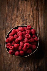 Raspberry in a ceramic bowl over wooden rustic background