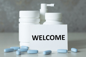 a card with the name of welcome pills are scattered nearby and bottles of medicine are standing. Medical concept.