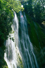 descending stream pure water in jungle forest. The photo of the waterfall was taken in the Dominican Republic in the rainforest. The picture of the jungle with water impresses with its pristine