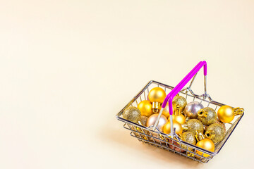 Shopping cart with golden Xmas balls on light background with copy space. Christmas sale, discounts, holiday shopping and buying gifts and presents concept.