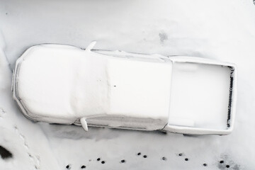 A parked pick up car  covered with snow after heavy snowfall, top view