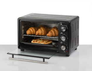 Opened electric oven with cooked bakery isolated on white background