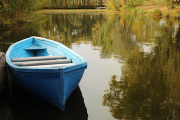 Light blue wooden boat on lake, space for text