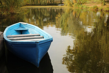 Fototapeta premium Light blue wooden boat on lake, space for text