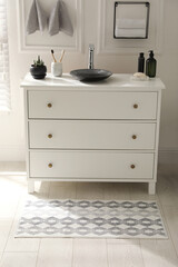 Stylish mat with pattern near chest of drawers in bathroom