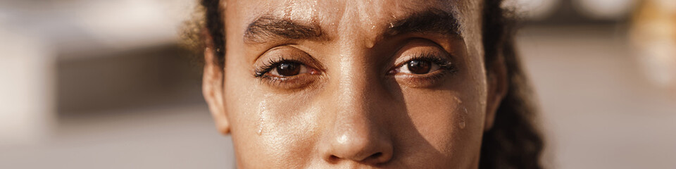 Black sportswoman looking at camera while working out on parking