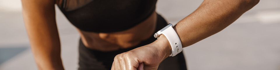 Black sportswoman looking at smartwatch while working out