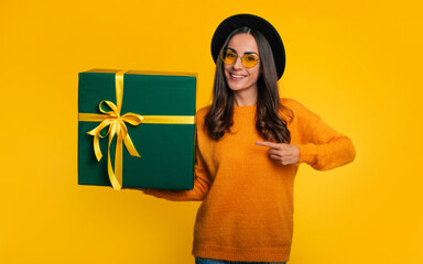 Attractive excited smiling young woman holds beautiful gift box in hands and looks on the camera...
