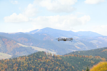 Fototapeta na wymiar Modern drone flying in mountains on autumn day