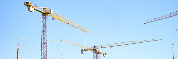 Naklejka premium Many construction cranes standing near multi-storey buildings at site background