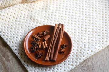 Plate of various winter spices and knitted blanket. Selective focus.