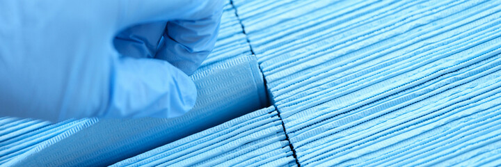 Doctor hand in rubber gloves pulling out sterile disposable napkin from packaging closeup