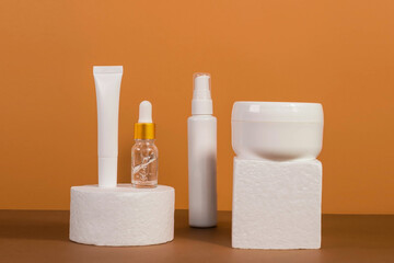 Copy space geometric shapes with night, day cream cosmetic oil, eye cream on yellow background. Unbranded bottles in mockup style. Beauty background with facial cosmetic products. Spa, beauty concept.