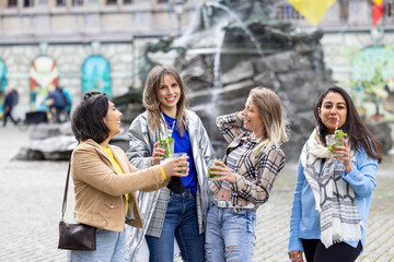 Muti ethnic group of female friends having fun drinking cocktails outdoor in the city in bar restaurant. High quality photo
