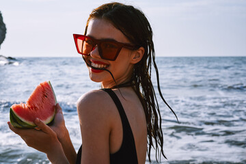 pretty woman in a black swimsuit with a watermelon in her hands summer Ocean