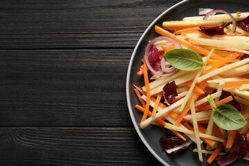 Plate with fresh turnip salad on dark wooden table, top view. Space for text