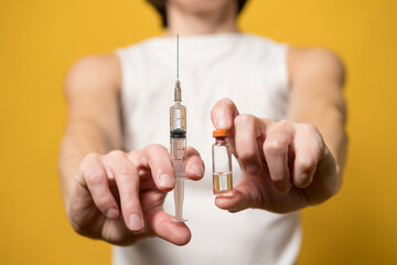 Hands hold a syringe filled with liquid and a vial with a vaccine. Concept of vaccination against...