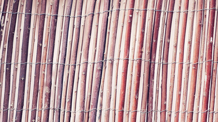 Wattle fence of dry twigs as the background. Traditional rustic fence. Abstract wooden backdrop.