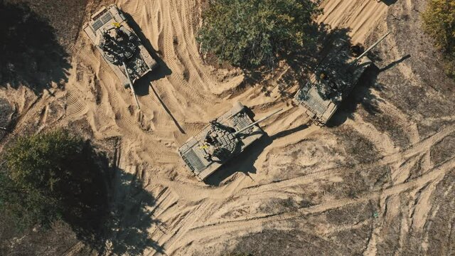 Group of tanks top down aerial view closeup. Strategic military army training. Armor camouflage transport troops. Warfare demonstration. Armored tanks on dry land battlefield. Tracking shot zoom out