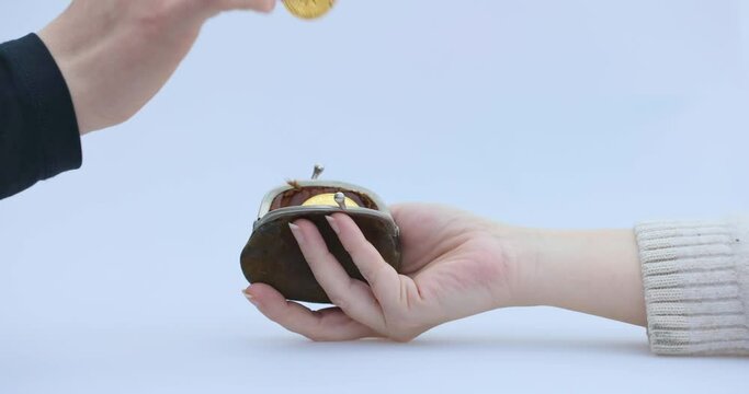 Male hand puts a cryptocoin, Bitcoin or BTC, in a small brown wallet, depicting earning or paying with crypto or cryptocurrency and saving, holding or hodling. High quality 4k footage