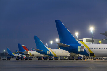 Passenger airplanes stand at the airport terminal at night