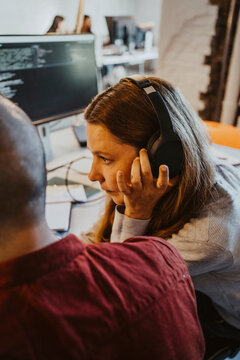 Female programmer listening through headphone while doing coding at startup company