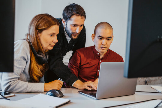 Female and male programmers concentrating while coding over laptop at office