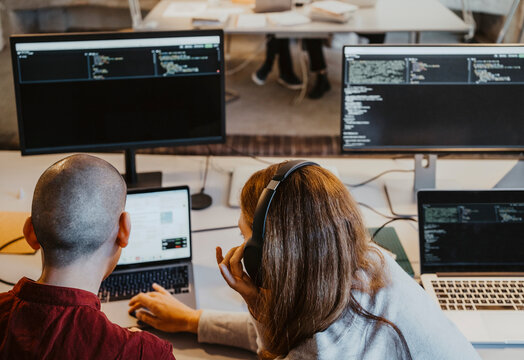 High angle view of female and male hackers coding over laptop in office