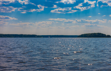 Summer landscape with a river on a background of blue sky with white clouds