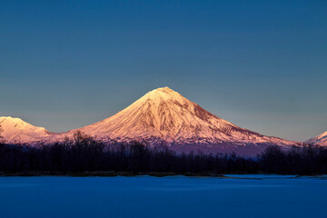 Snow-capped mountain in the evening light of the setting sun. Hill, winter landscape.