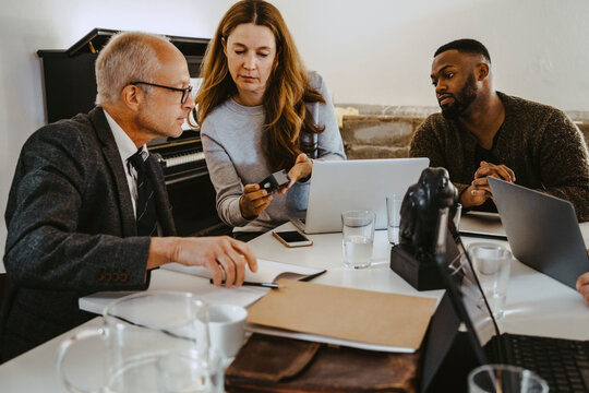 Female hacker discussing over satellite finder with male advisor in creative office