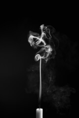Vertical shot of the smoke of an extinguished candle isolated on a black background