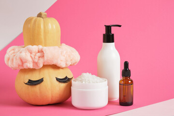 mock up set of cosmetic containers and pumpkin with headband and false eyelashes on pink background
