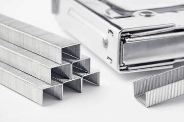 Close up of stack of metal staples for stapler gun on white background. Industrial tool.