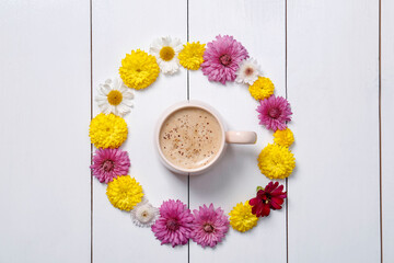 Beautiful floral composition with cup of hot coffee on white wooden background, flat lay