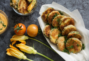 Breaded fried zucchini with tomatoes and sauce on dark background. Healthy lifestyle concept 