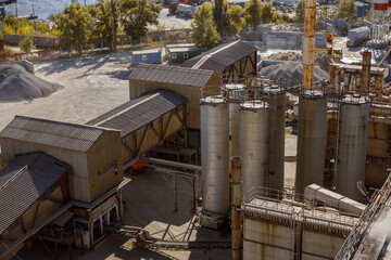 Cement factory with various installations, industrial facilities, metal storage containers, warehouses and piles of concrete sand mix