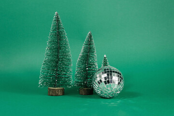 Christmas Christmas disco ball with christmas trees on green background.