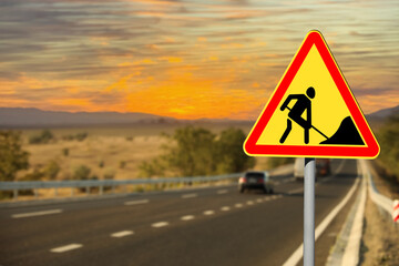 Traffic sign Road Works near highway at sunset