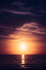 the sun sets over the beach in a purple and dramatic sky