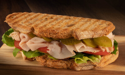 Tasty pastrama sandwich with roasted bread and vegetables on wood background