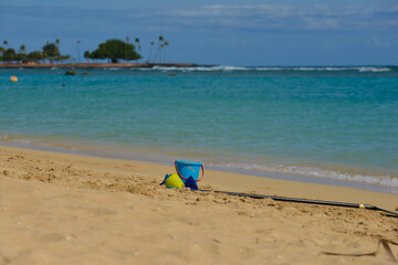 Fototapeta na wymiar Childs bucket and spade lying at the waters edge of tropical beach a perfect vacation spot. 