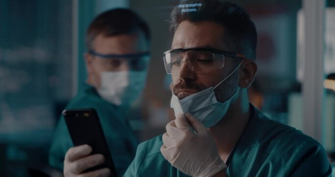 Male doctor unlocking smartphone with face scan