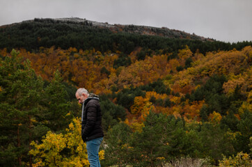 Portrait of adult man in black winter jacket against autumn color trees on mountain, in Tejera Negra, Cantalojas, Guadalajara, Spain