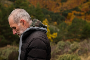 Portrait of adult man in black winter jacket against autumn color trees on mountain, in Tejera Negra, Cantalojas, Guadalajara, Spain