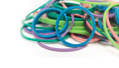 Pile of rubber bands or elastic loops in a variety of colors and sizes. Stationary office supply to bundle, organize and do art with. Close up. Isolated on white. Selective focus.