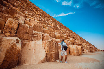 A man tourist stands near the huge blocks of the Giza pyramid near Cairo.