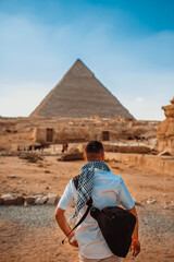 A tourist man stands with his back to the camera and looks at the pyramids. Meditation near the...