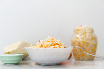 Homemade sauerkraut on white plate. Fermented cabbage with carrot on a light background. Eco food, the trend of healthy eating.